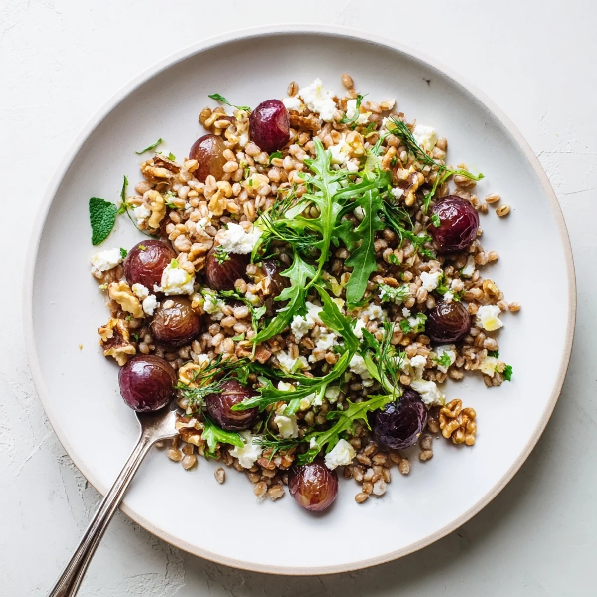 Wholesome roasted grape and walnut farro grain salad featuring arugula and crumbled feta cheese