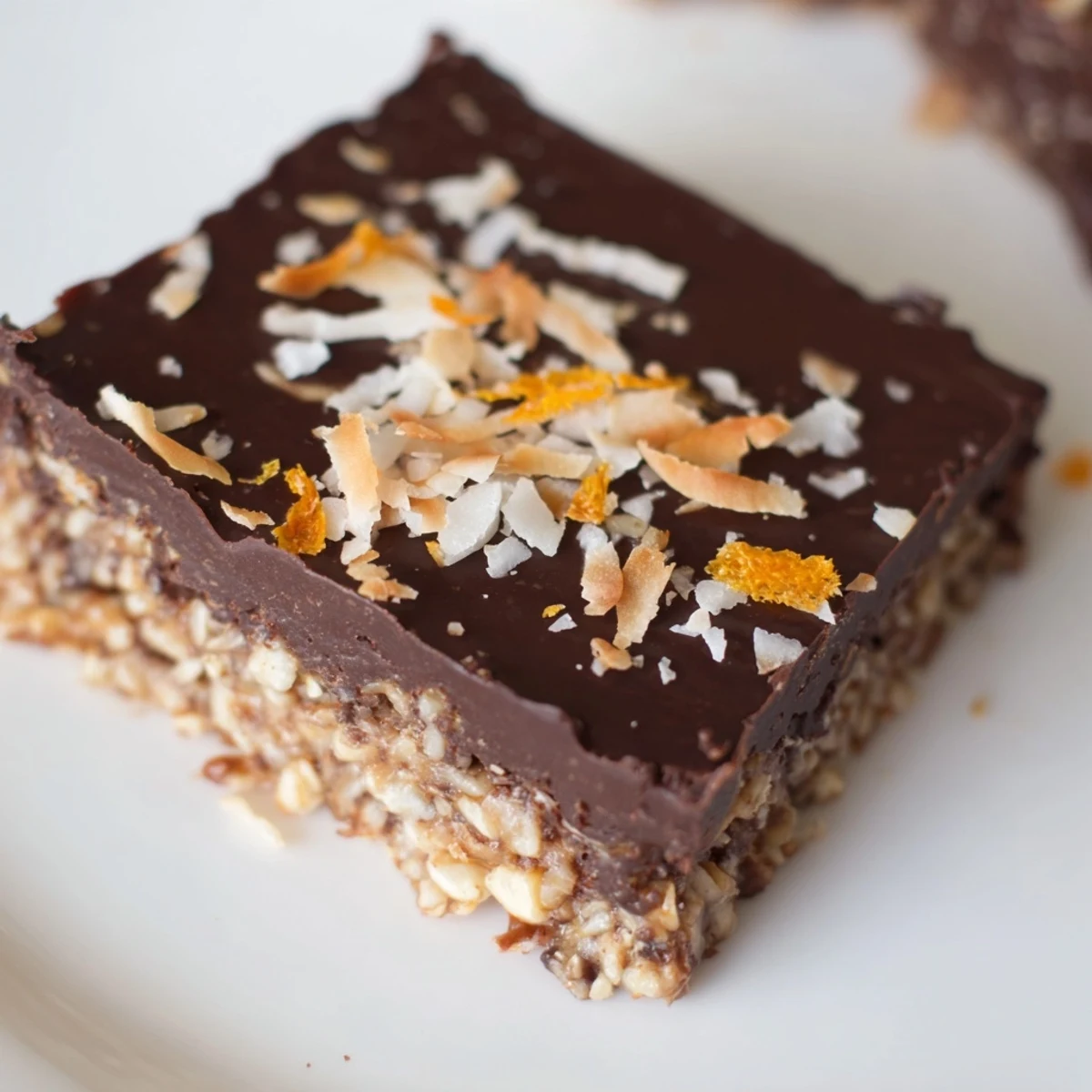 Golden chocolate orange coconut bliss bars topped with toasted flakes and zesty orange garnish