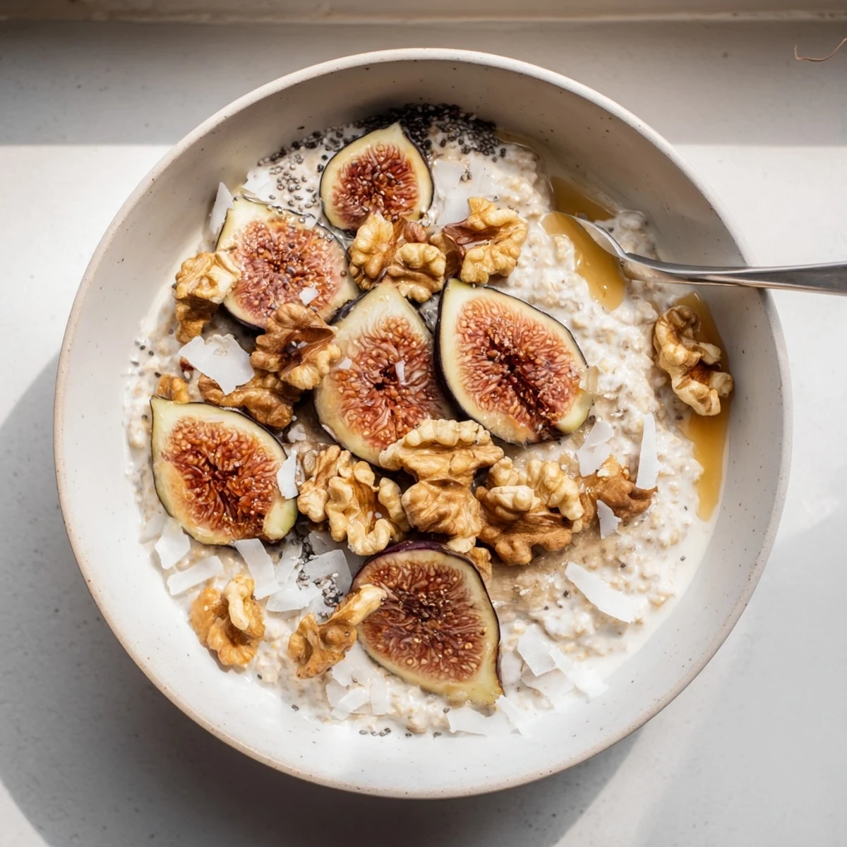 Breakfast bowl featuring vanilla fig overnight oats garnished with coconut, walnuts, and fresh fruit