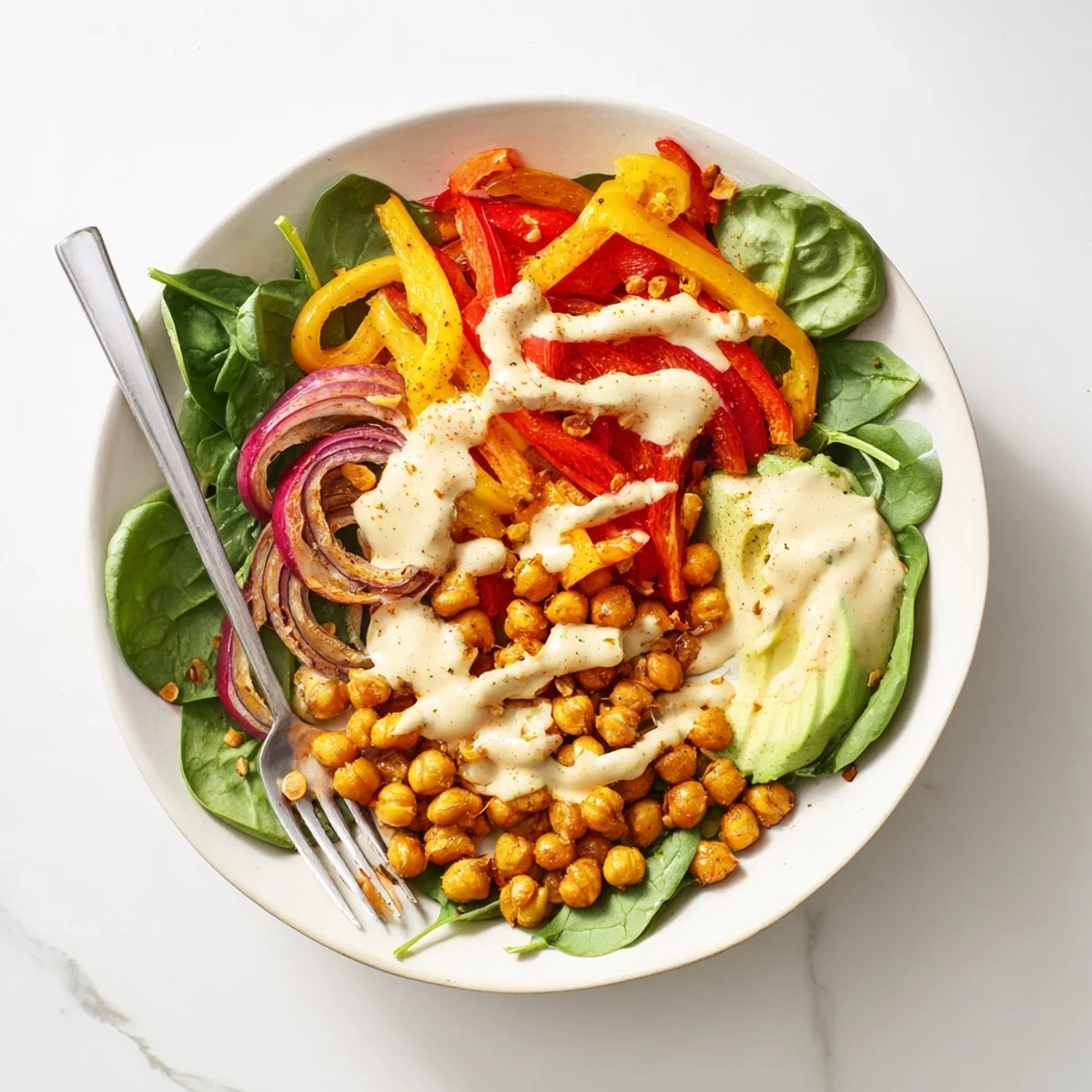 Colorful savory roasted pepper chickpea breakfast bowl topped with creamy avocado and fresh greens