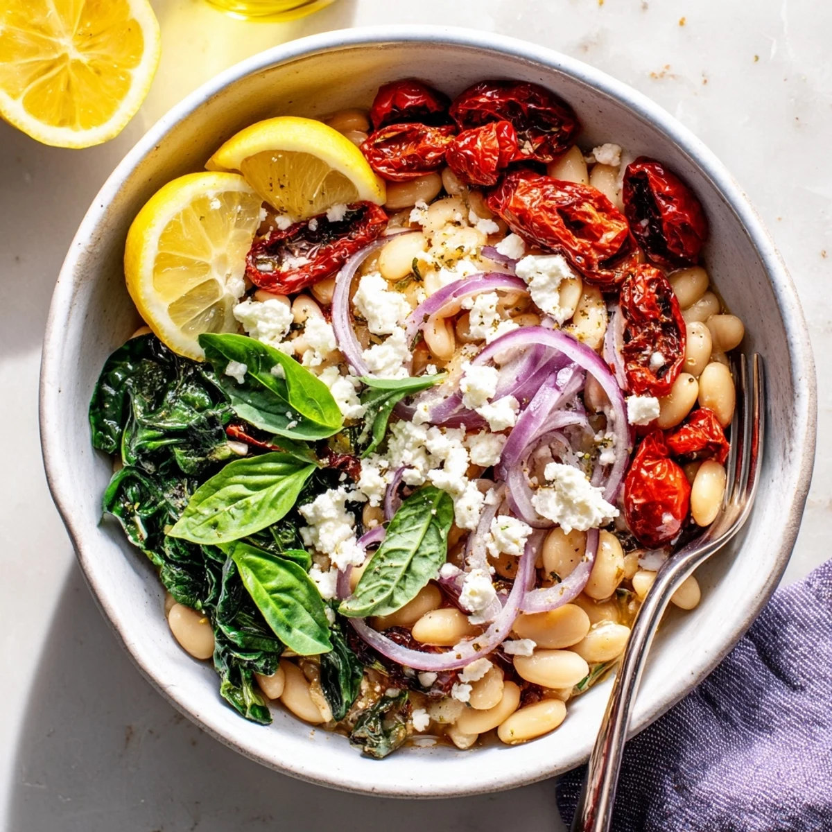 Creamy white bean breakfast bowl topped with sun-dried tomatoes, fresh basil, and crumbled feta cheese