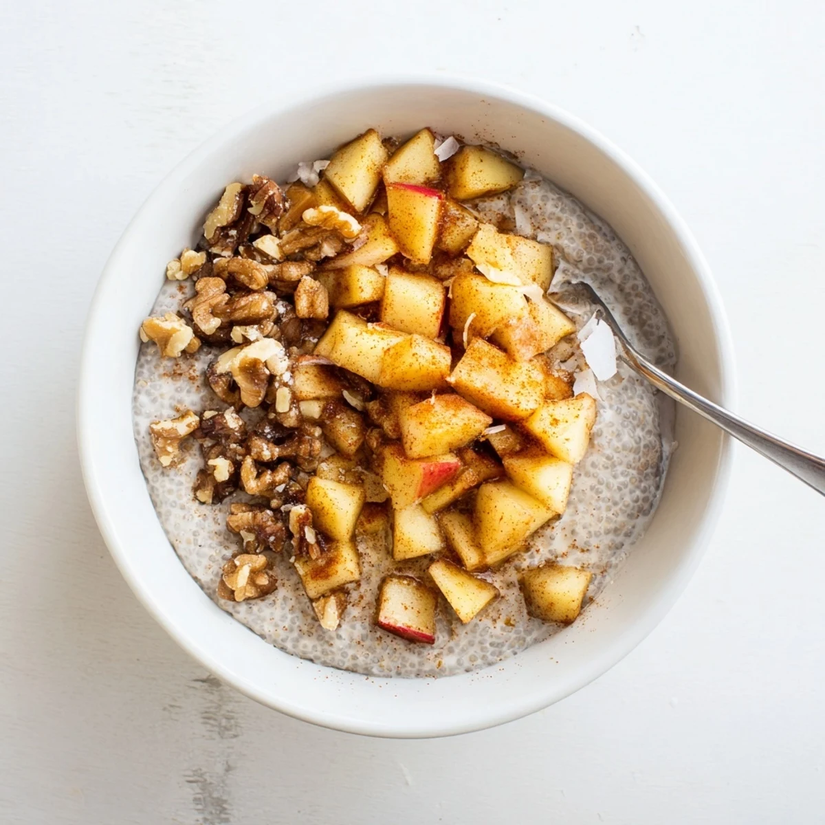 Close up of cinnamon apple chia overnight breakfast bowl with coconut flakes and pecans