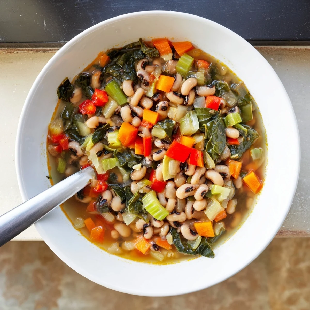 Steamy bowl of smoky black-eyed pea and greens soup with tender collard pieces floating in rich vegetable broth