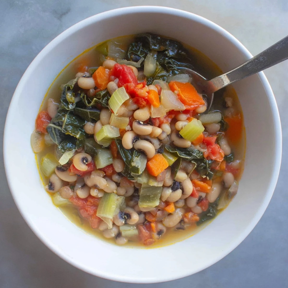 Rustic black-eyed pea and greens soup featuring vibrant vegetables and smoky aromatics, ladled into a deep serving bowl