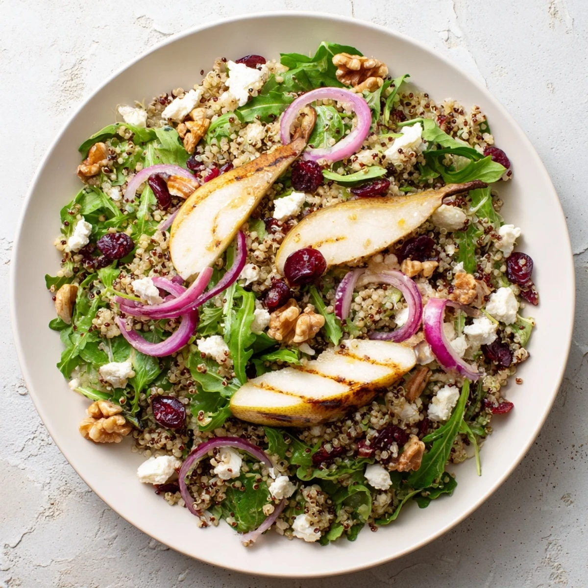 Fresh bowl of grilled pear and walnut quinoa grain salad with feta and cranberries