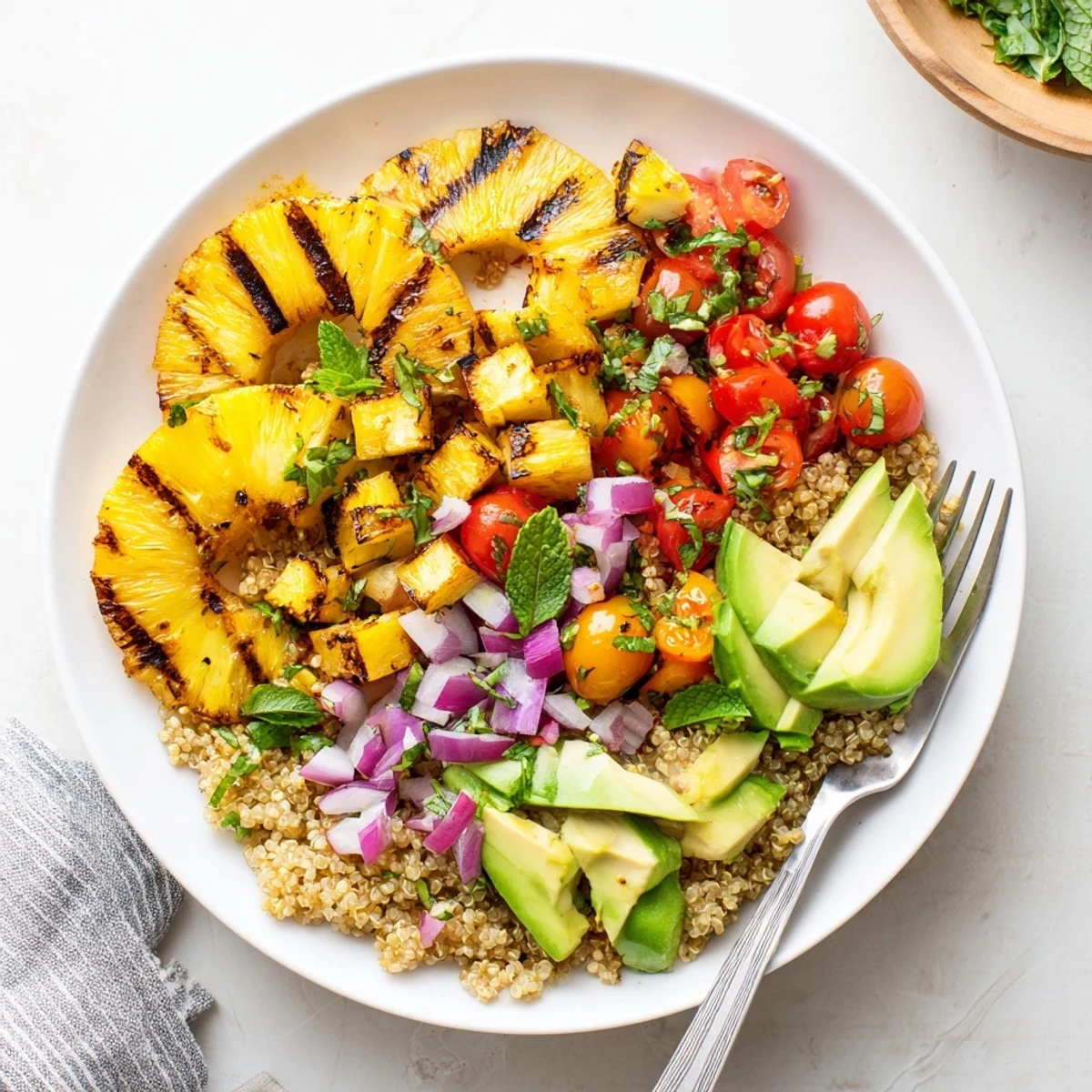 Colorful grilled pineapple chili quinoa grain salad with charred fruit and fresh vegetables in a bowl
