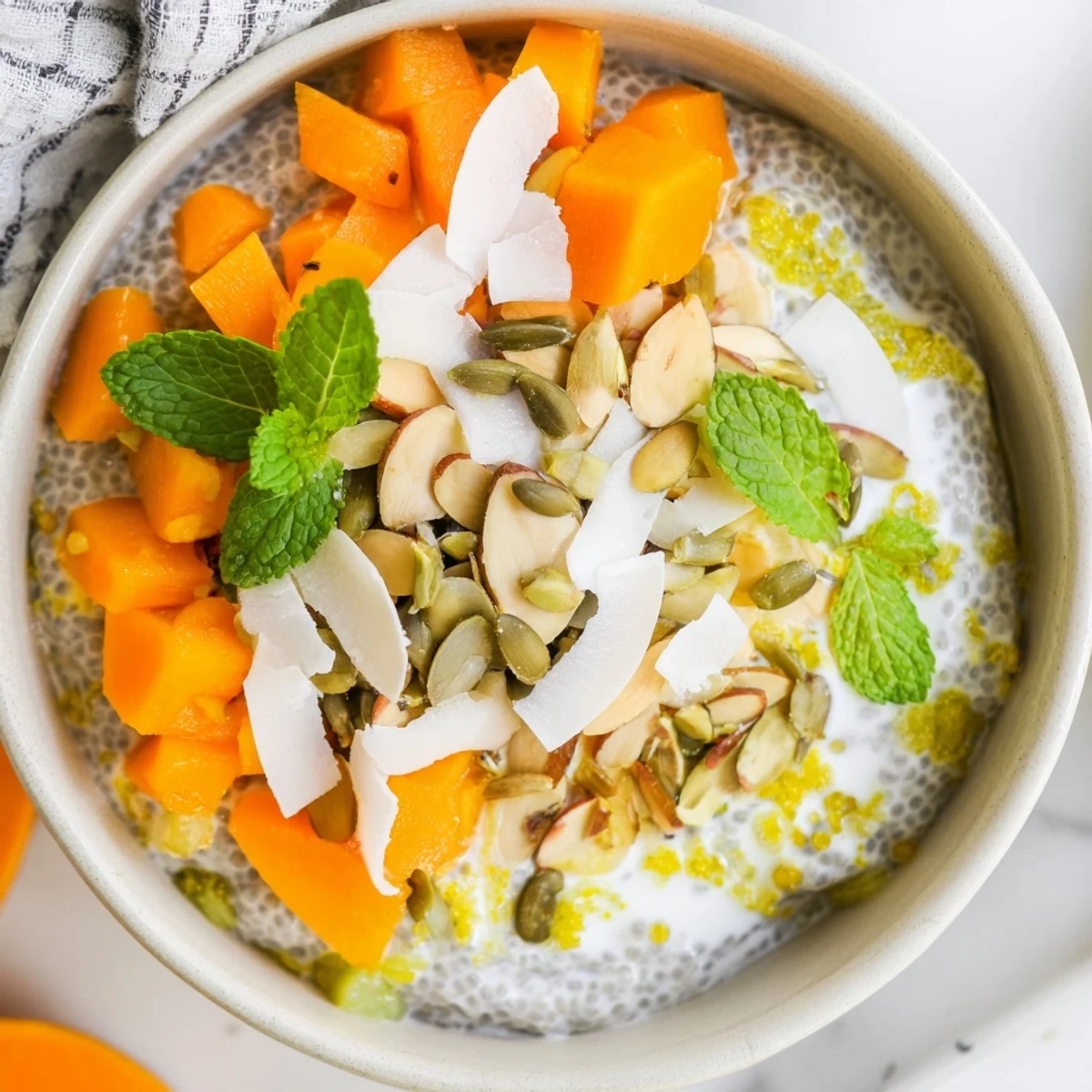 Creamy coconut lime chia breakfast bowl featuring vibrant diced papaya and textured nut and seed toppings