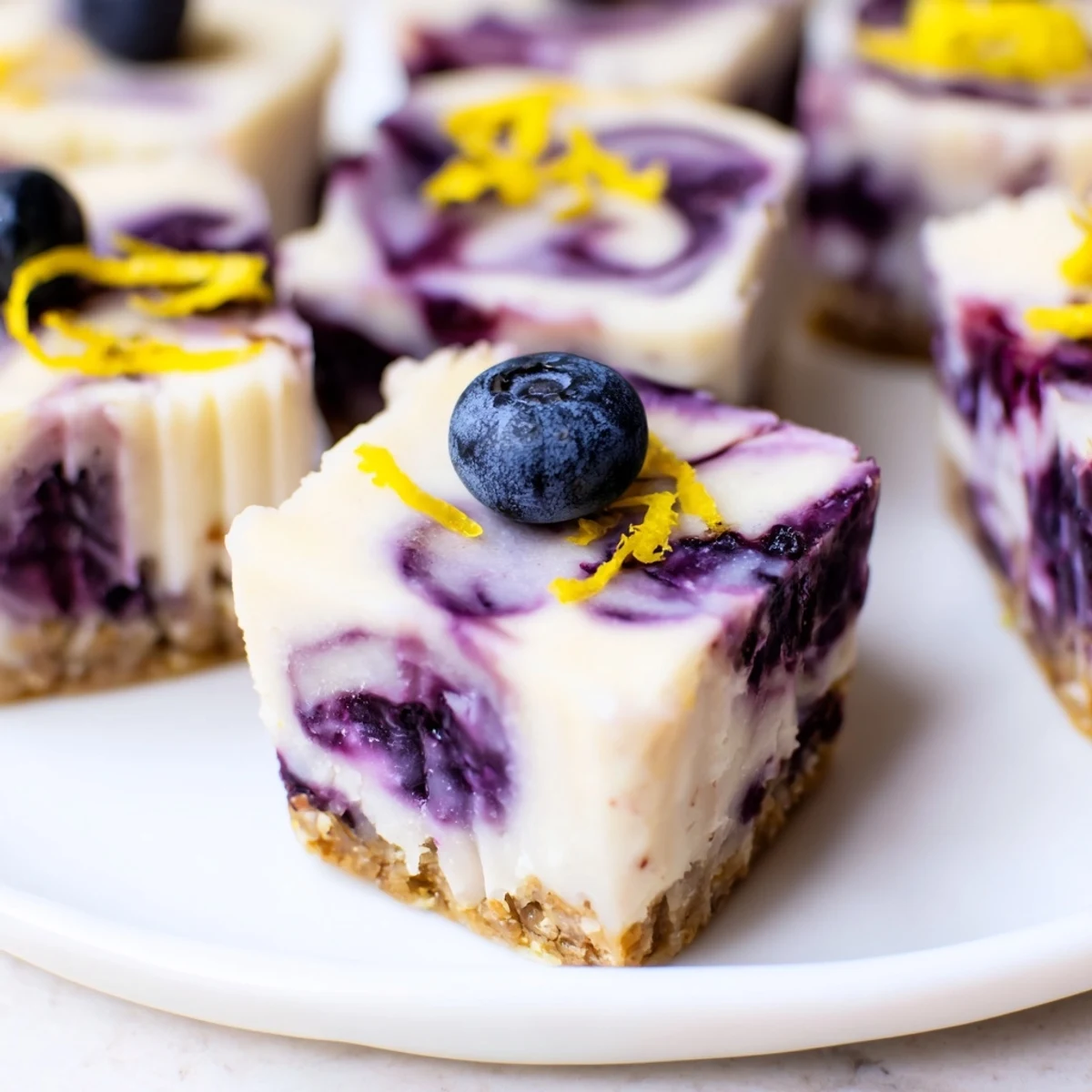 Creamy blueberry lemon cashew cheesecake bites swirled with purple blueberry topping on almond crust