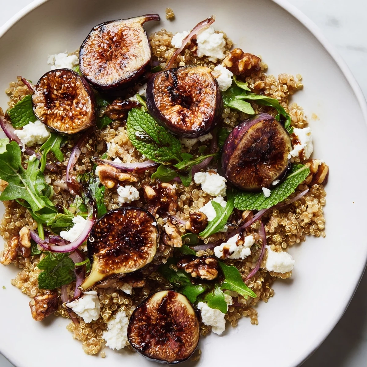 Grilled fig and balsamic quinoa grain salad topped with crumbled goat cheese and toasted walnuts