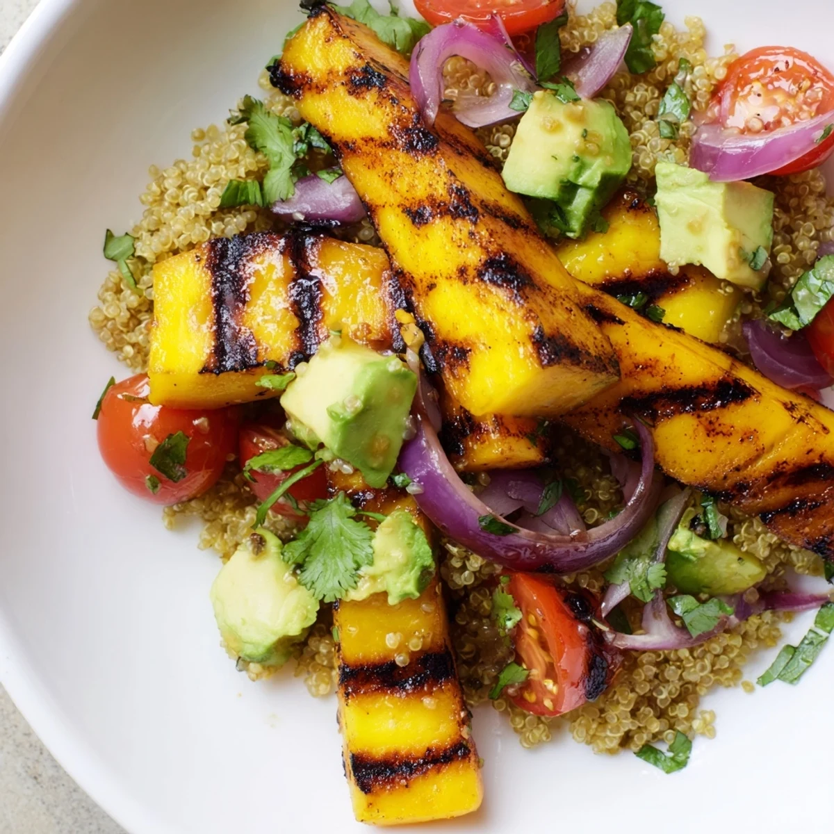 Grilled Mango Avocado Quinoa Grain Salad topped with caramelized fruit and fresh herbs