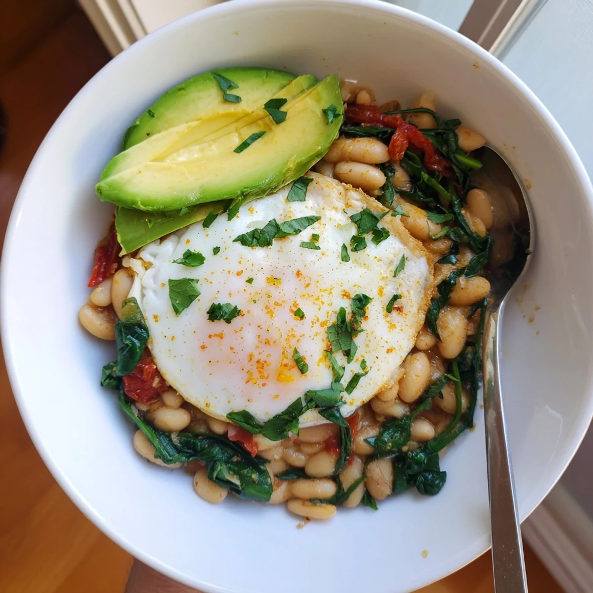 Warm spiced white bean and spinach breakfast bowl served in a rustic dark ceramic dish