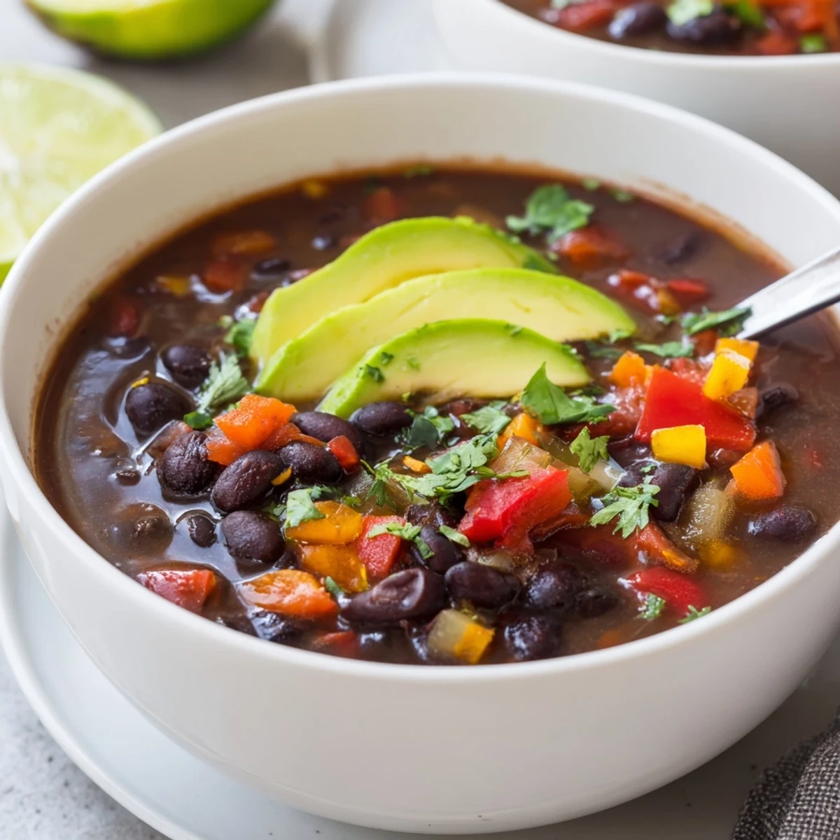 Ladle serving of Smoky Black Bean and Roasted Pepper Hearty Soup with lime