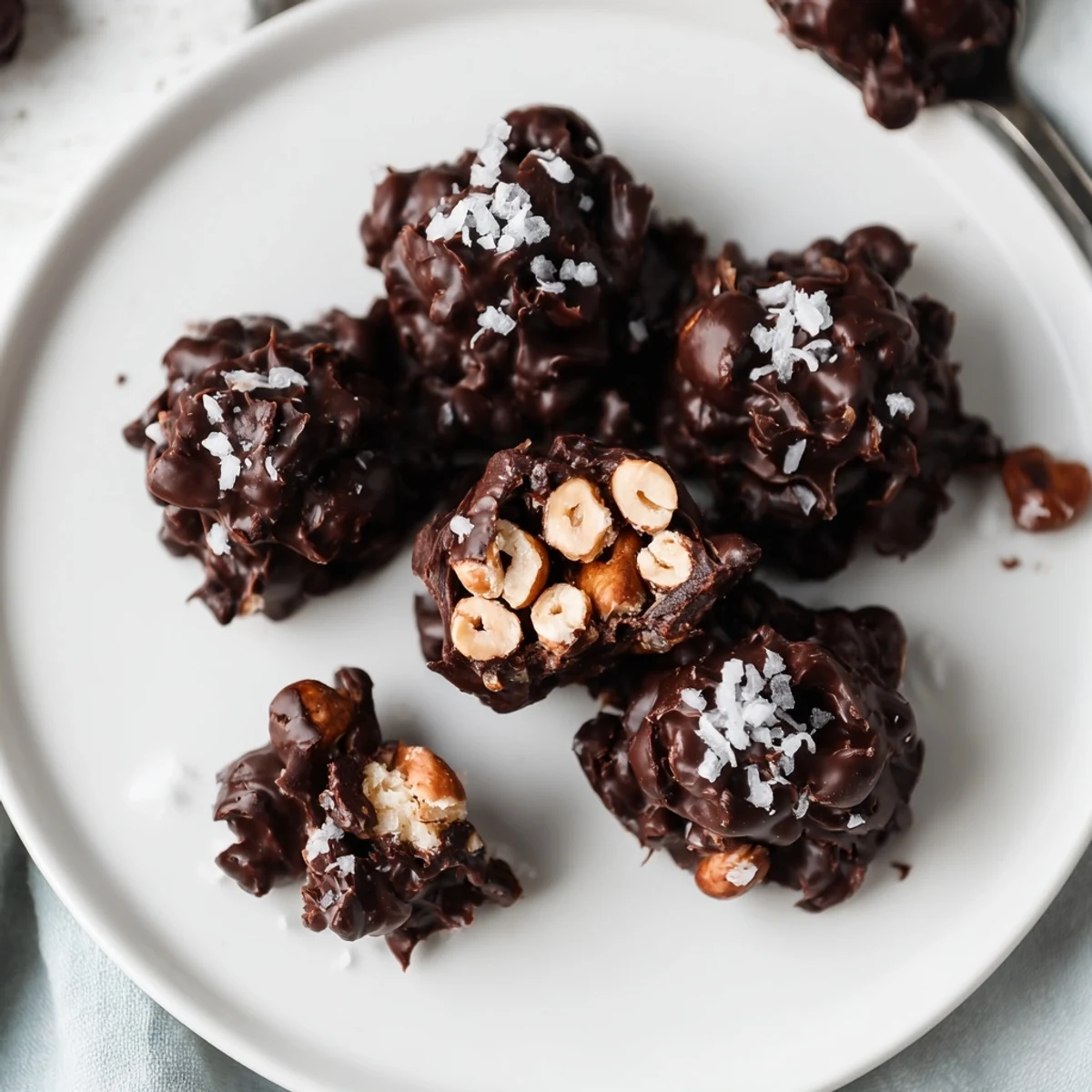 Dark Chocolate Hazelnut Coconut Clusters piled on parchment, glossy chocolate, crunchy nuts