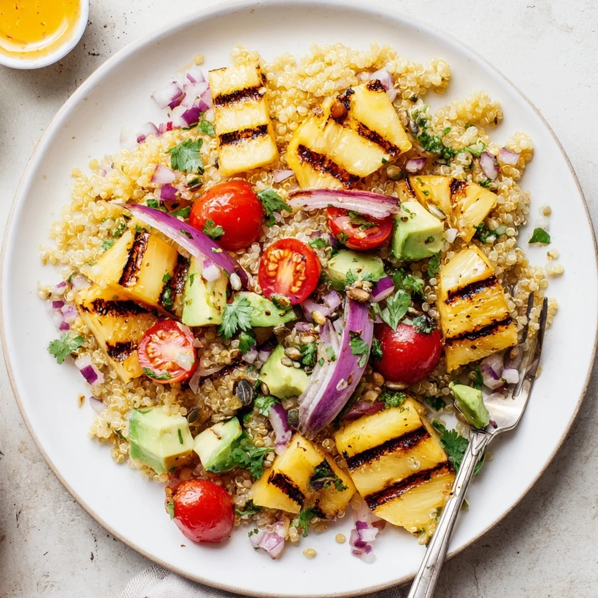 Grilled Pineapple Cilantro Quinoa Grain Salad piled in bowl, garnished with toasted pumpkin seeds
