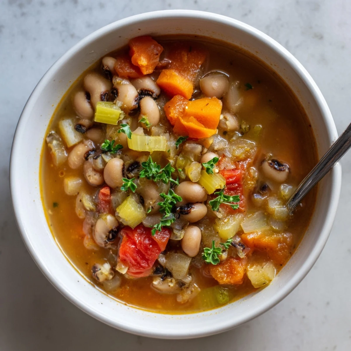 Vegan smoky black eyed pea and tomato hearty soup paired with crusty bread on a wooden cutting board