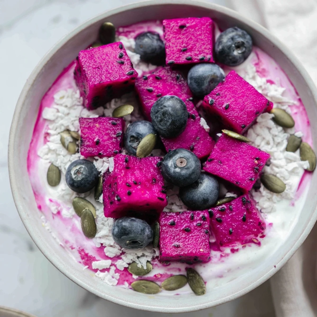 Vibrant pink dragonfruit layered over creamy coconut lime chia pudding with fresh fruit and crunchy toppings