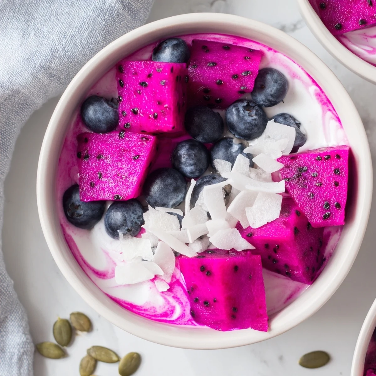 Colorful dragonfruit coconut lime chia breakfast bowl topped with fresh berries, shredded coconut, and pumpkin seeds
