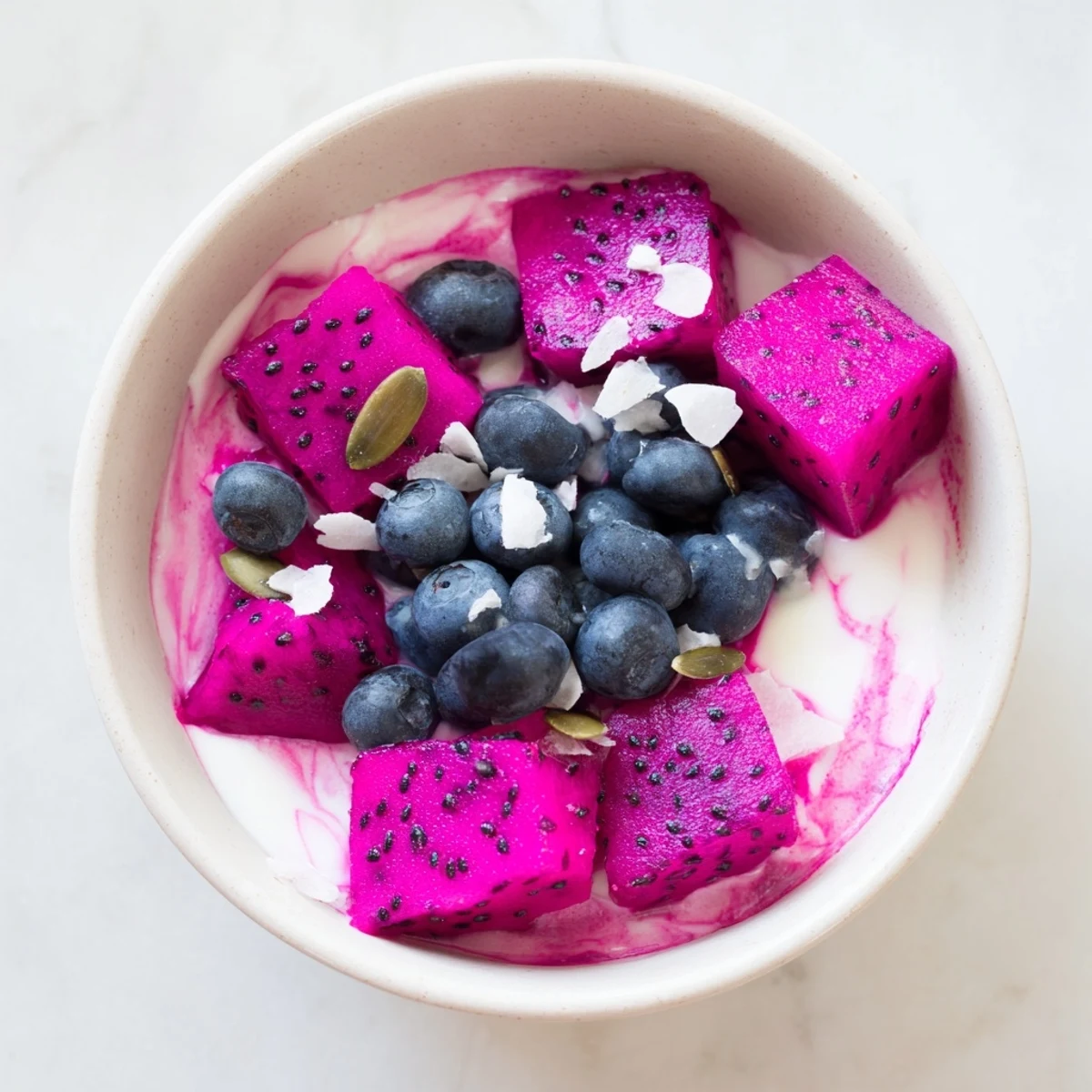 Tropical dragonfruit coconut lime chia breakfast bowl featuring swirled pink layers, toasted coconut, and fresh lime