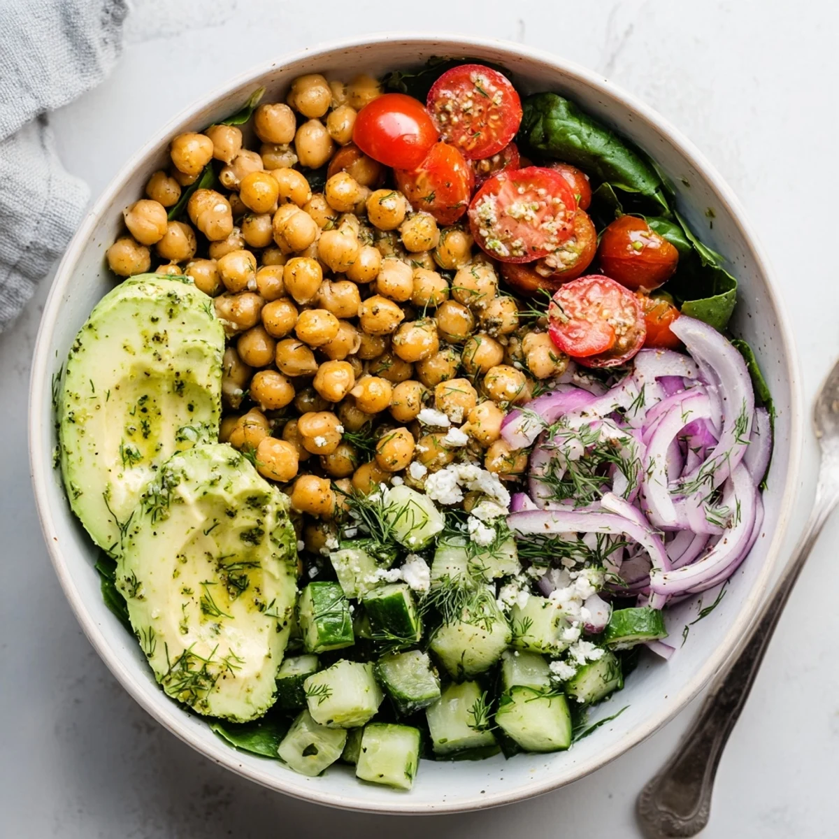 Golden chickpea breakfast bowl with fresh spinach avocado and tangy lemon dill dressing in rustic ceramic bowls
