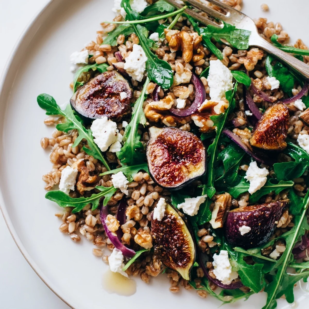 Mediterranean-style bowl featuring caramelized figs over fluffy farro greens with tangy lemon vinaigrette