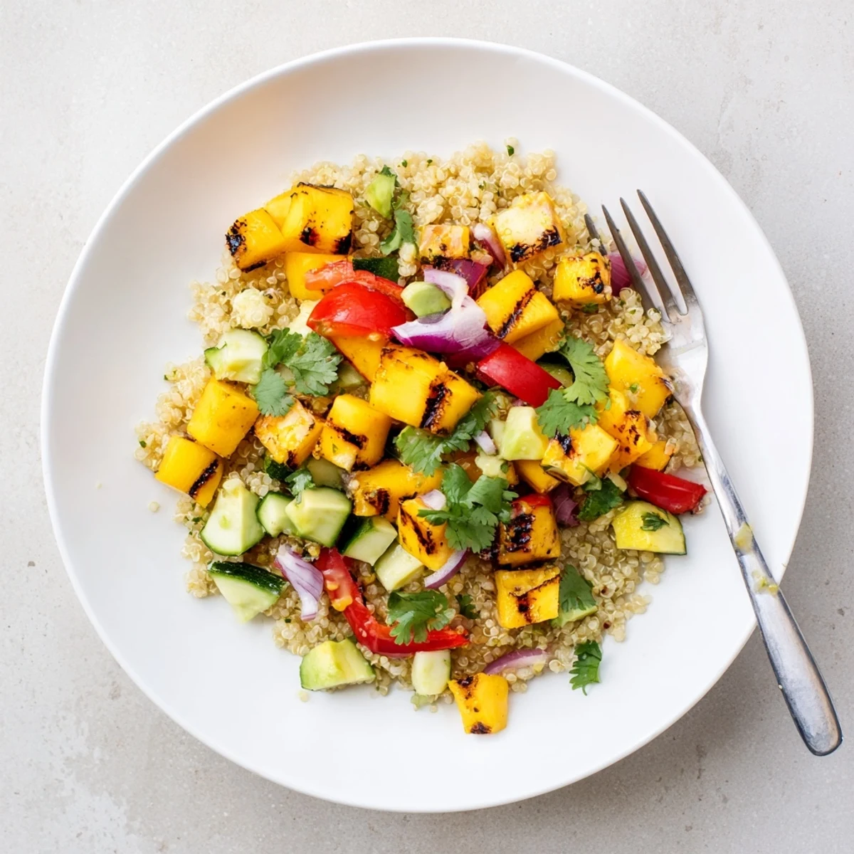 Colorful grilled mango chili quinoa grain salad bowl with fresh vegetables and zesty lime dressing