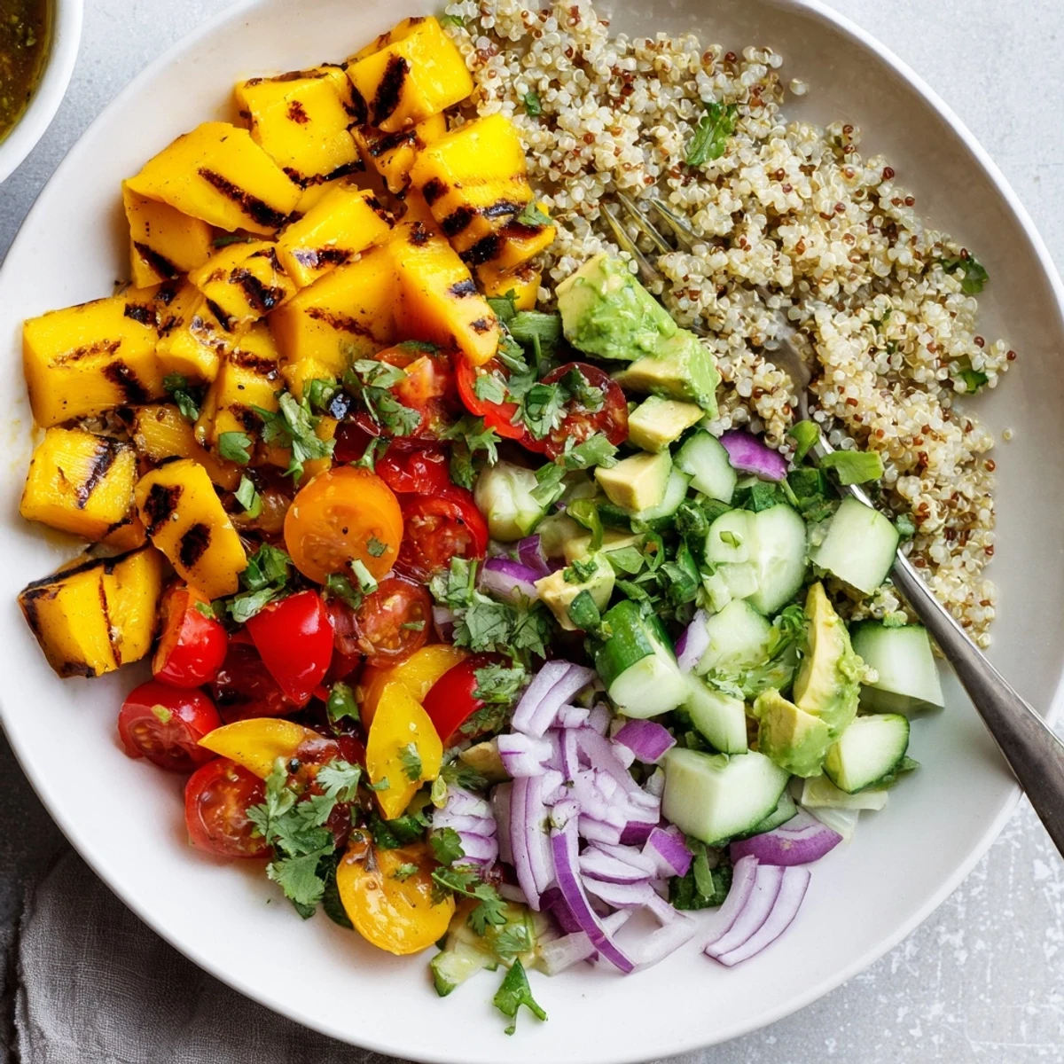 Close-up of vibrant grilled mango chili quinoa grain salad featuring avocado and cherry tomatoes