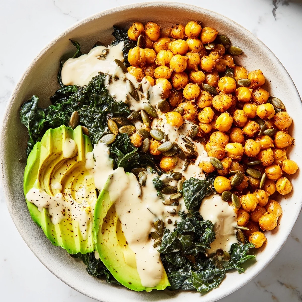 Vegan turmeric chickpea and kale breakfast bowl with smooth tahini sauce and fresh avocado slices