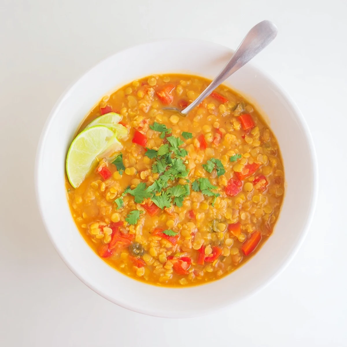 Steaming bowl of hearty spiced coconut tomato split lentil soup topped with green cilantro leaves