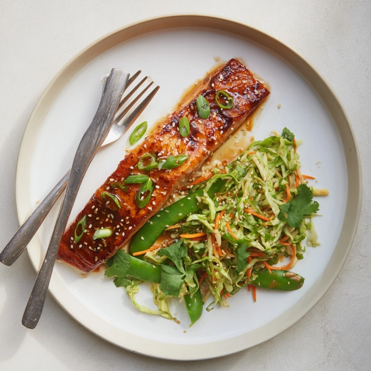 Tender baked salmon glazed in sweet miso maple sauce served over vibrant shredded cabbage slaw