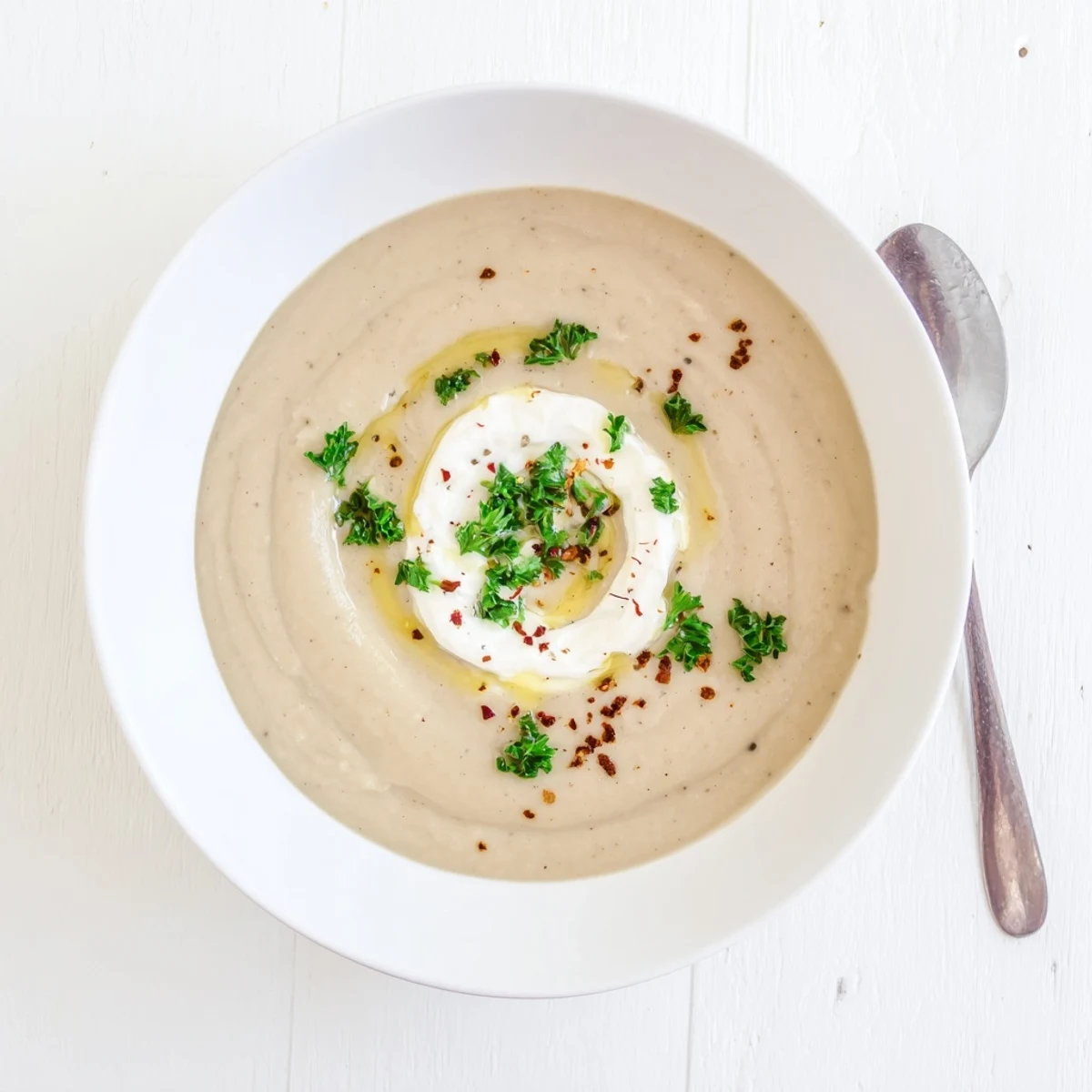 Golden bowl of hearty Mediterranean roasted eggplant and white bean soup drizzled with olive oil and red pepper flakes