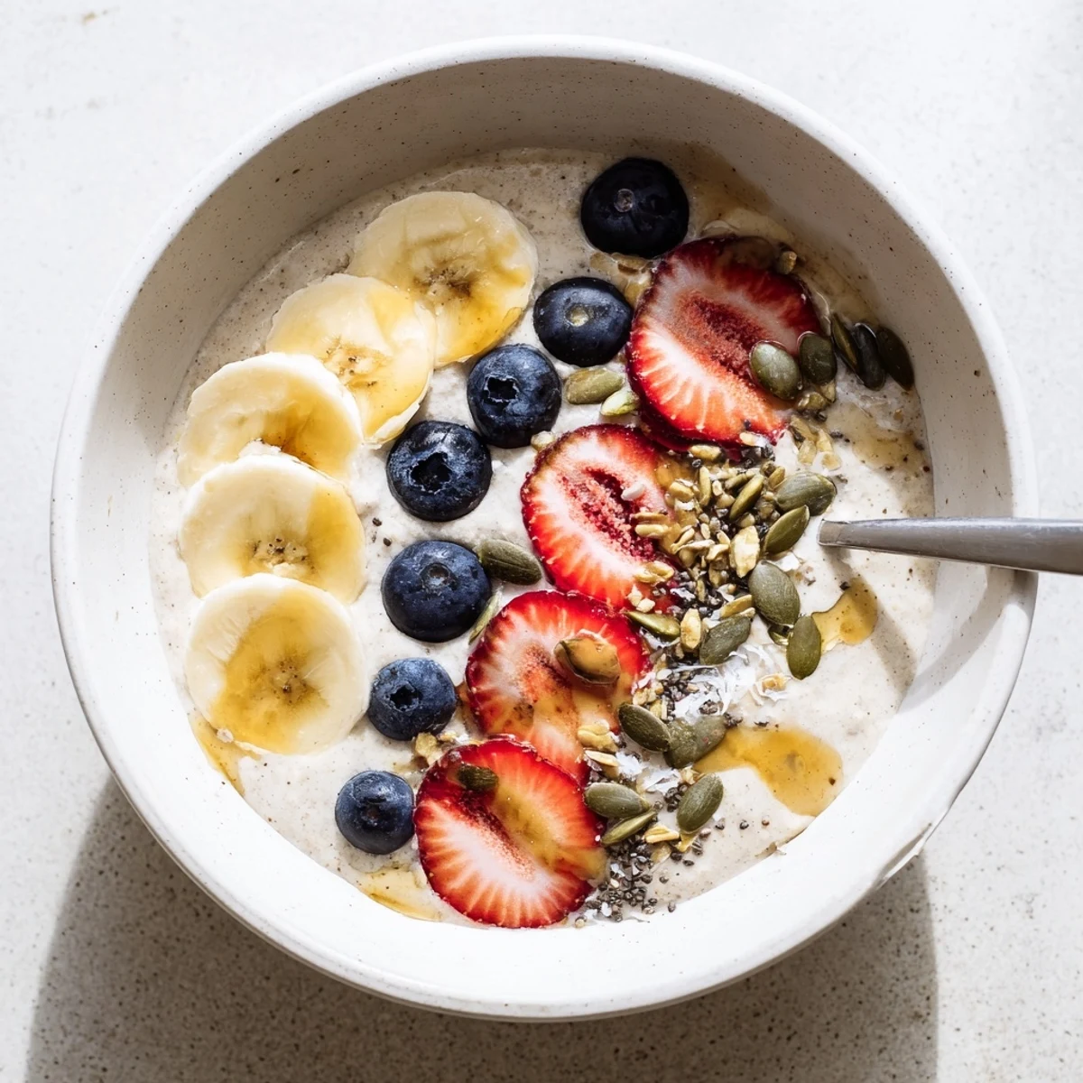 Vanilla maple teff porridge bowl topped with fresh berries banana slices and crunchy seeds