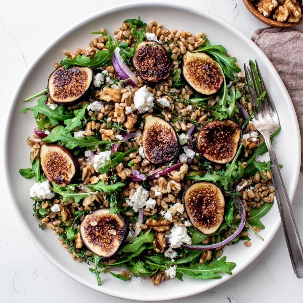 Hearty roasted fig thyme farro salad with creamy cheese, crunchy nuts, and tender fresh greens