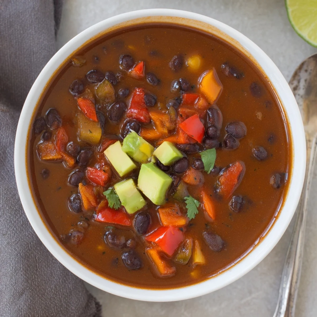 Bowl topped with lime and cilantro, Smoky Black Bean and Roasted Pepper Hearty Soup.