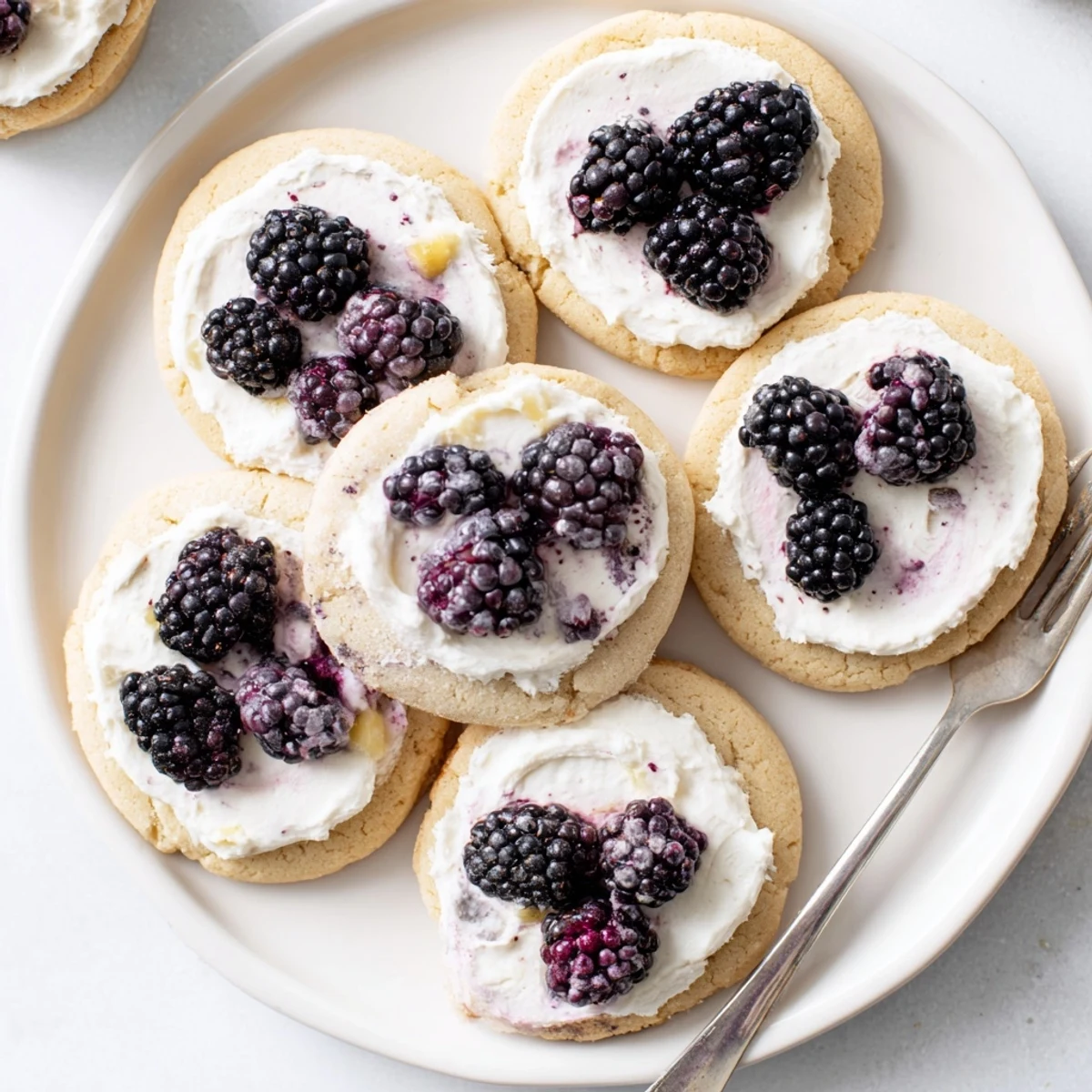 Chewy plant-based sugar cookies sandwiched with tangy pineapple blackberry cream filling on a rustic wooden serving board