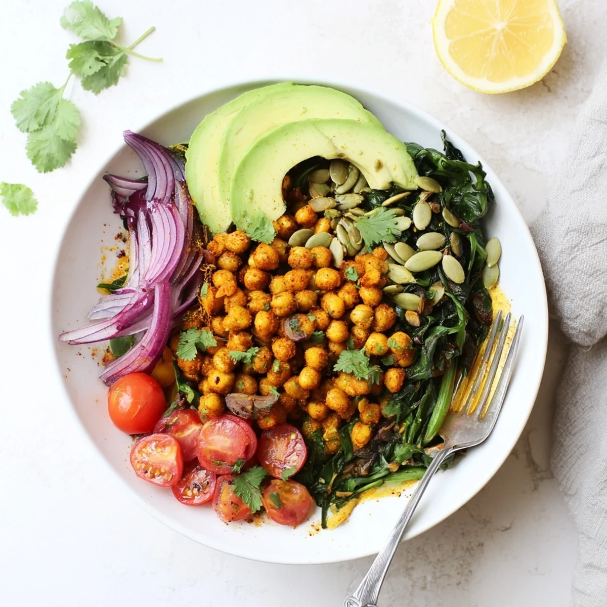 Warm spiced chickpeas nestled over sautéed Swiss chard with bright lemon and sliced avocado