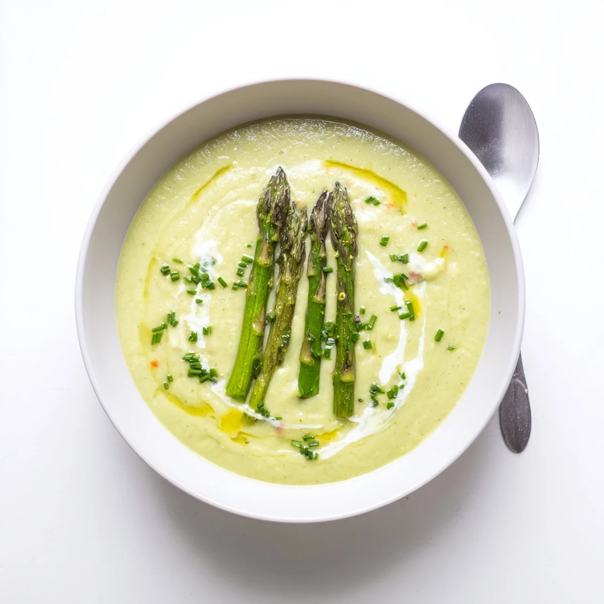 Creamy roasted asparagus tip and white bean hearty soup ladled into a rustic bowl with fresh chive garnish