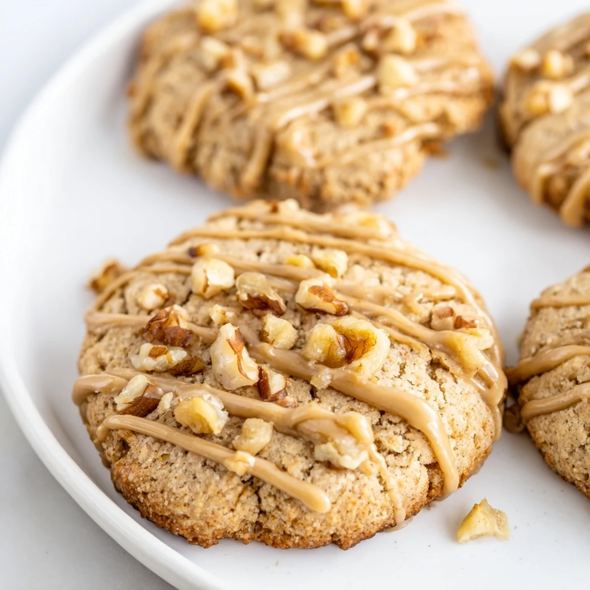 Warm keto maple walnut butter drizzle cookies with crunchy chopped walnuts and sweet maple icing