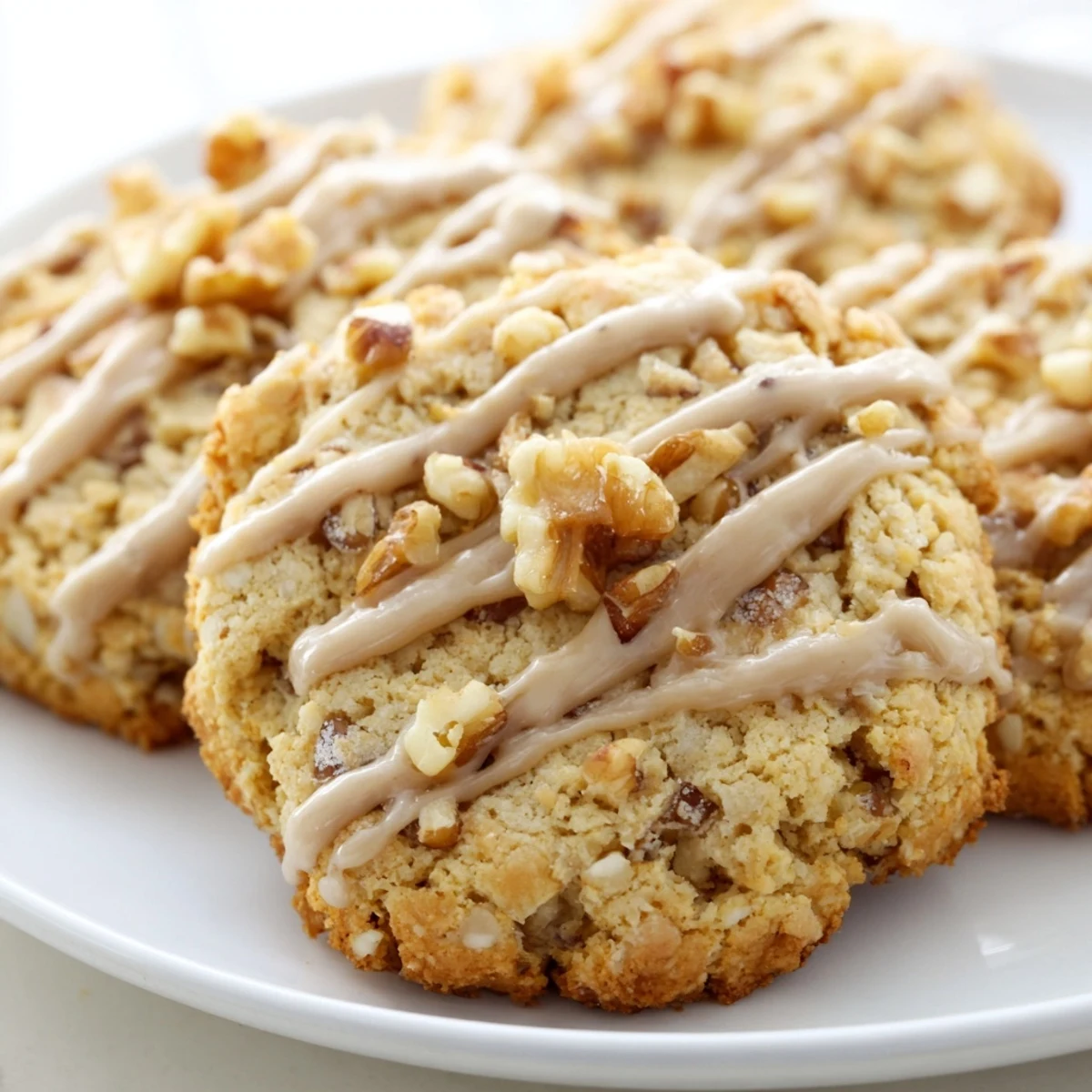 Freshly baked keto maple walnut butter drizzle cookies arranged on a rustic white serving plate