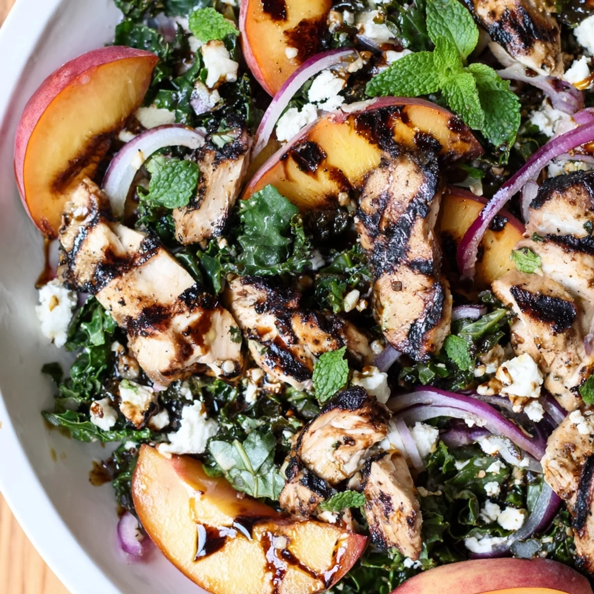 Grilled Peach and Kale Chicken Salad topped with crumbled feta on a rustic plate