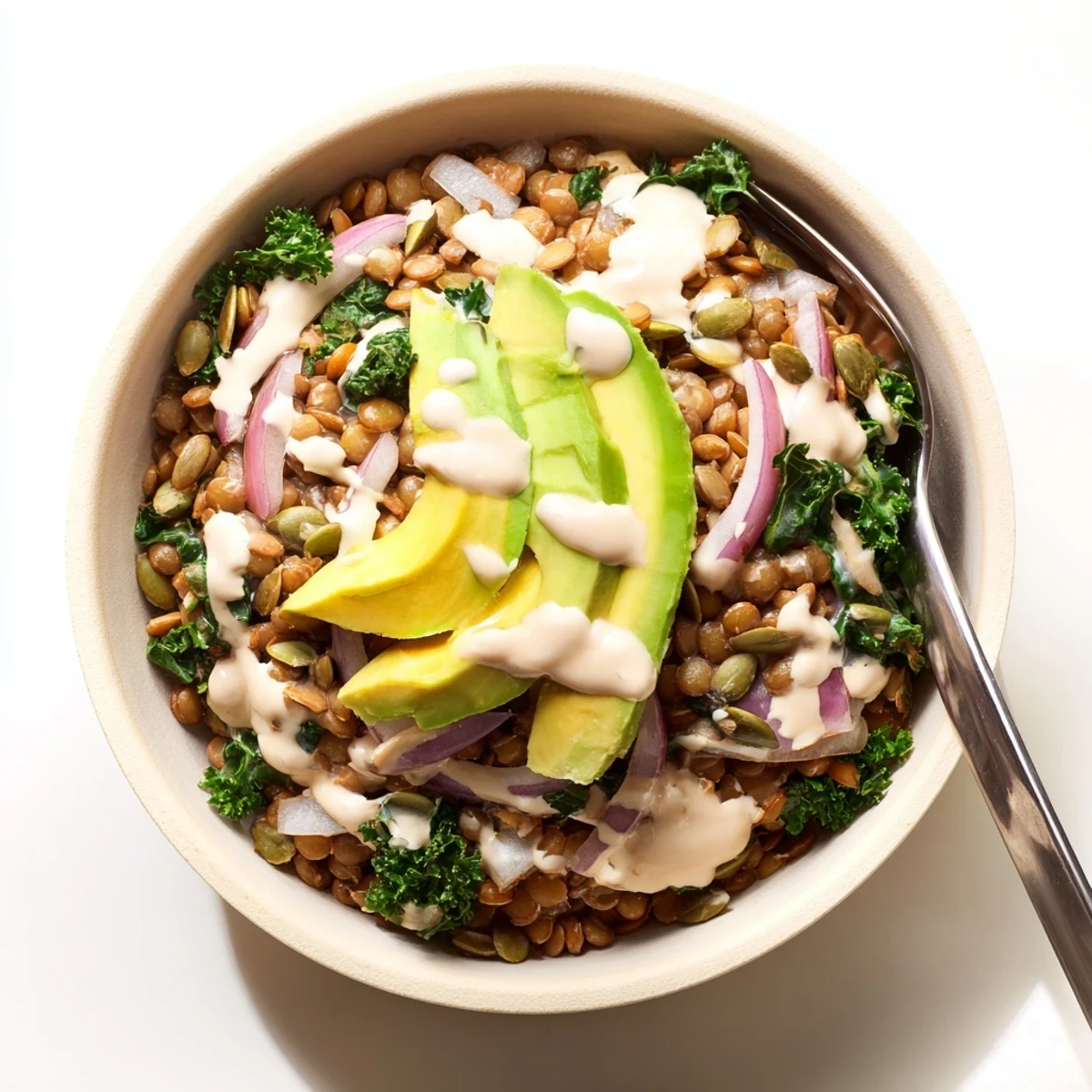 Nourishing vegan meal with lentils and spinach topped with tahini and seeds.