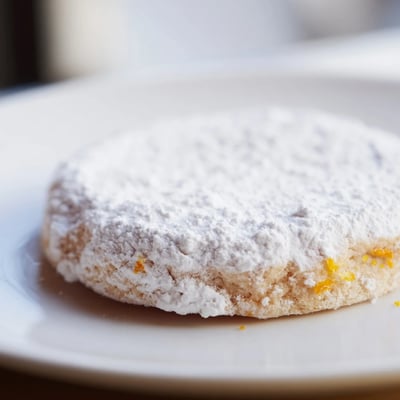 A stack of warm Seasonal Citrus Cookies on a rustic wooden table, showcasing tender crumb and vibrant citrus zest flecks inside.