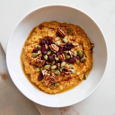 A cozy bowl of pumpkin spice millet breakfast bowl with warming autumn spices and toasted pumpkin seeds garnish.