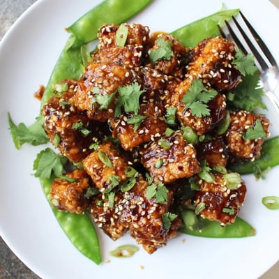 Crunchy sesame snap peas topped with saucy crispy chili garlic tofu and fresh cilantro